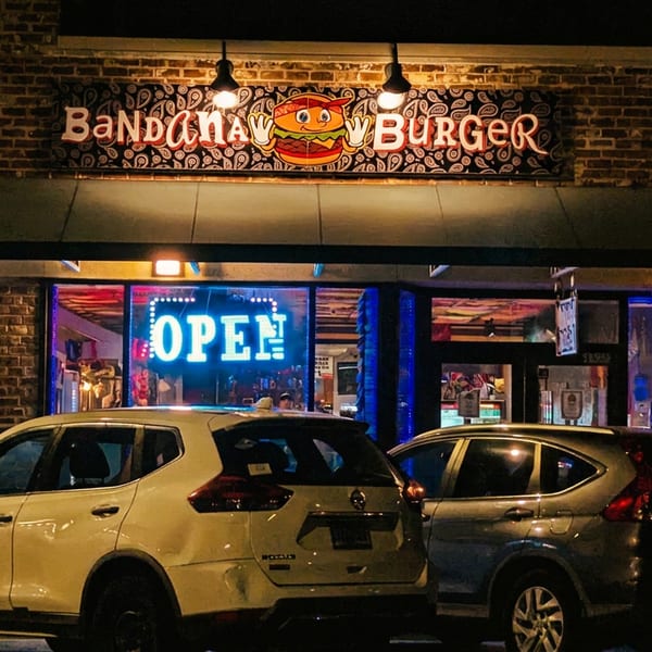 Bandana Burger restaurant at night with an "OPEN" neon sign and cars parked in front.