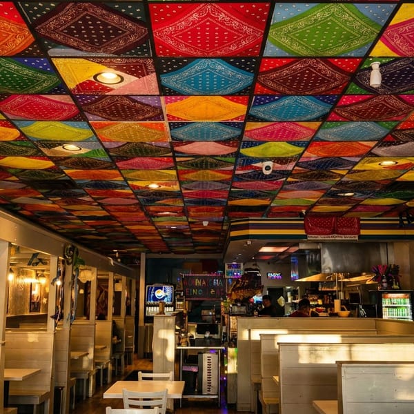 A vibrant restaurant interior with a ceiling covered in colorful bandanas and rows of booths.