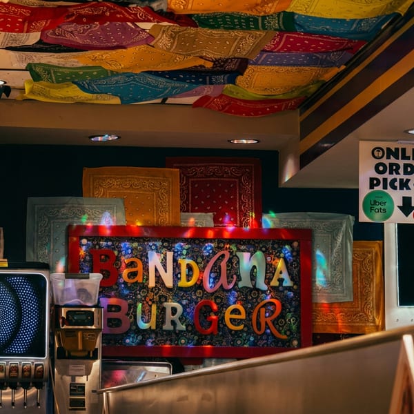 Interior of Bandana Burger restaurant with colorful bandanas on the ceiling and a "Slush Surget" machine.